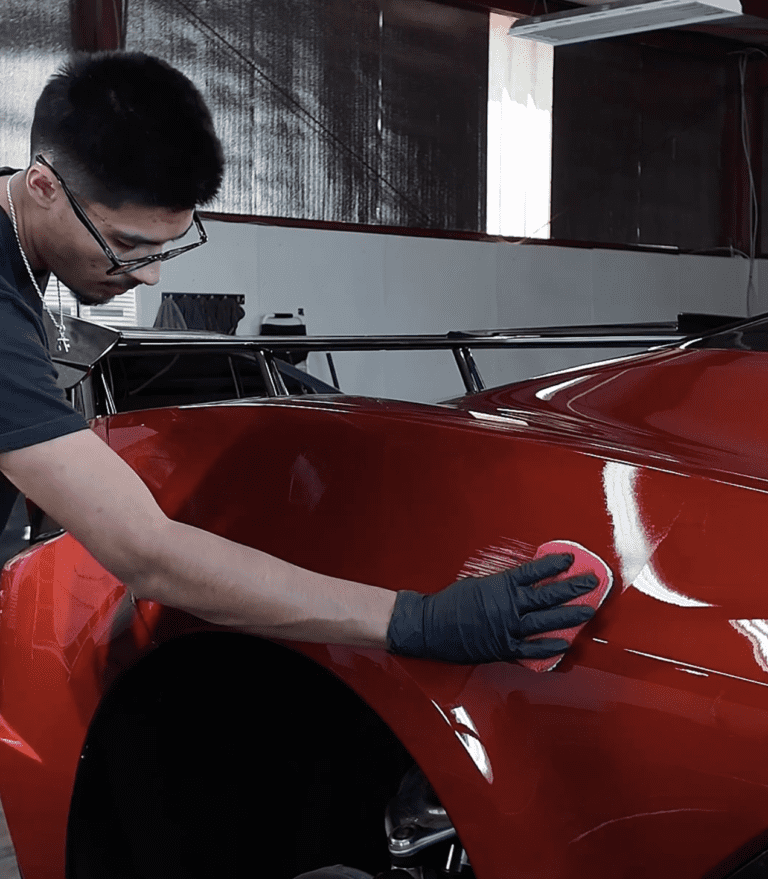 Auto detailing technician polishing a red car hood
